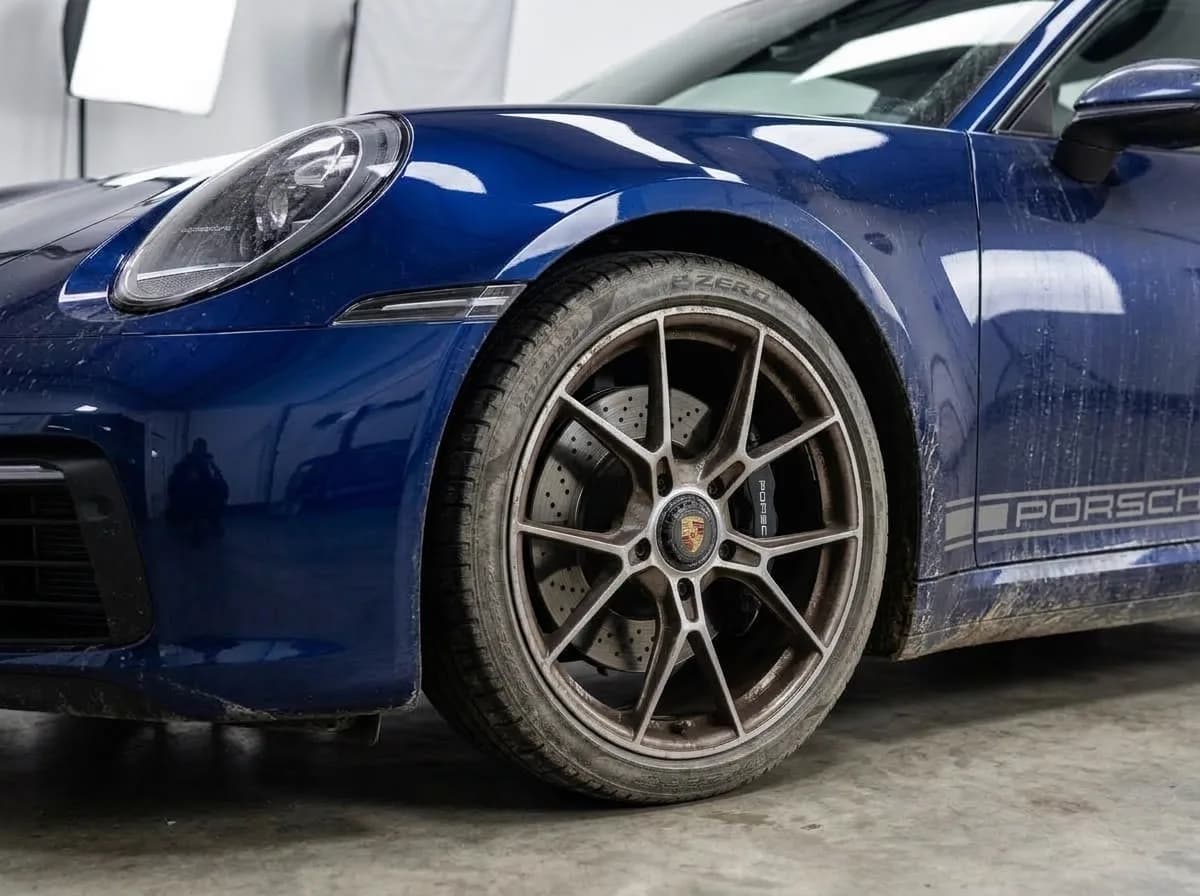 Vehicle wheel, tire and exterior panels covered in road grime and brake dust before mobile detailing